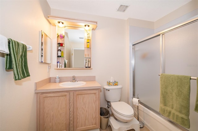 bathroom featuring visible vents, shower / bath combination with glass door, toilet, and vanity
