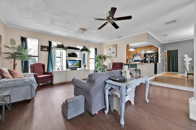 living room with hardwood / wood-style flooring, ceiling fan, and crown molding