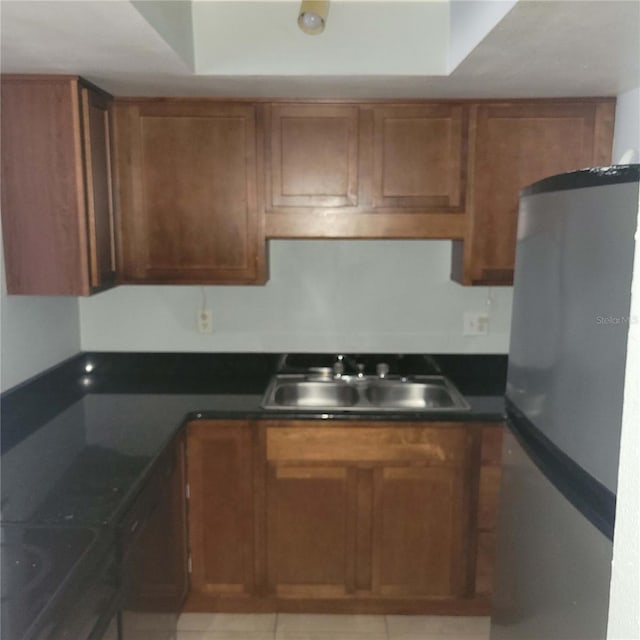 kitchen featuring stainless steel fridge, sink, and light tile patterned floors