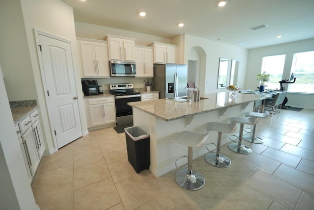 kitchen with an island with sink, appliances with stainless steel finishes, sink, and white cabinets