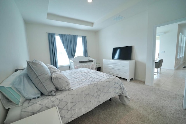 carpeted bedroom with a tray ceiling