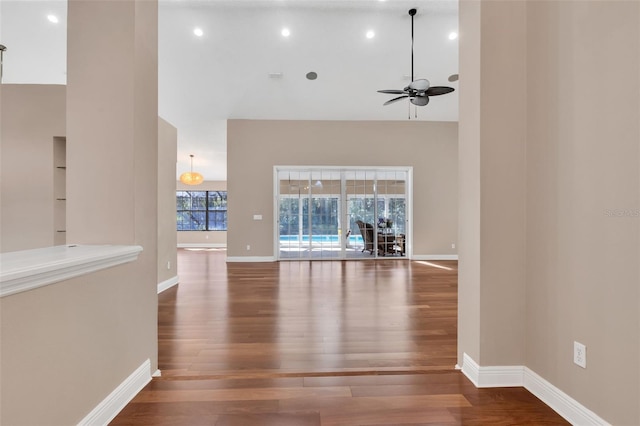 unfurnished living room featuring a towering ceiling, hardwood / wood-style floors, and ceiling fan