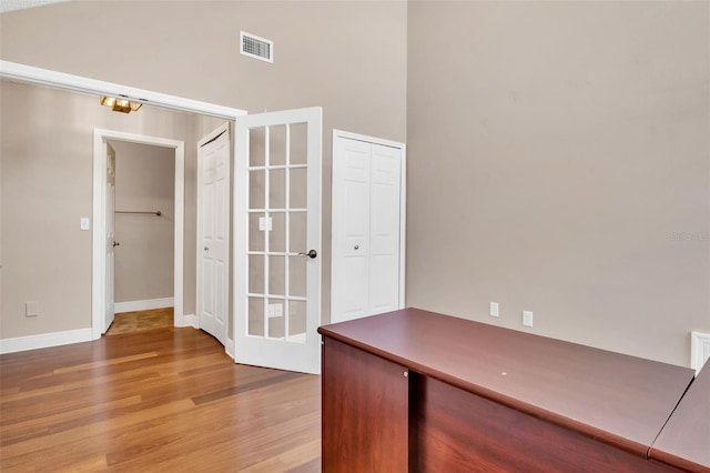 unfurnished office featuring hardwood / wood-style floors and a towering ceiling