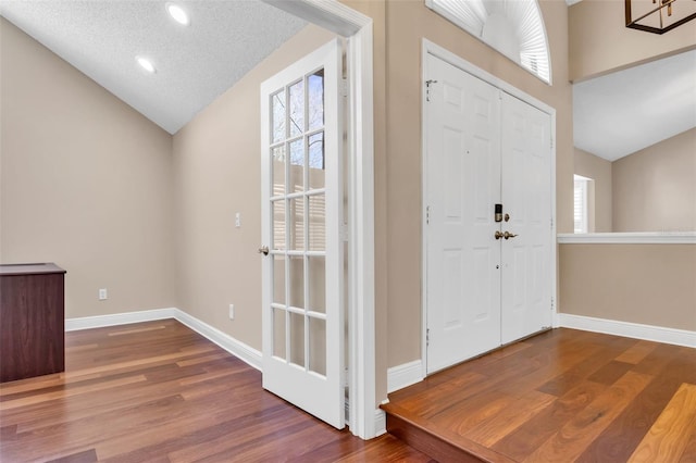 foyer featuring hardwood / wood-style flooring, lofted ceiling, and a textured ceiling