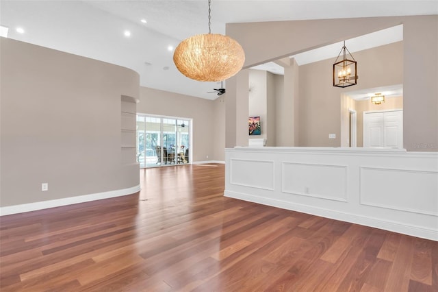 unfurnished room featuring hardwood / wood-style floors, ceiling fan with notable chandelier, and high vaulted ceiling