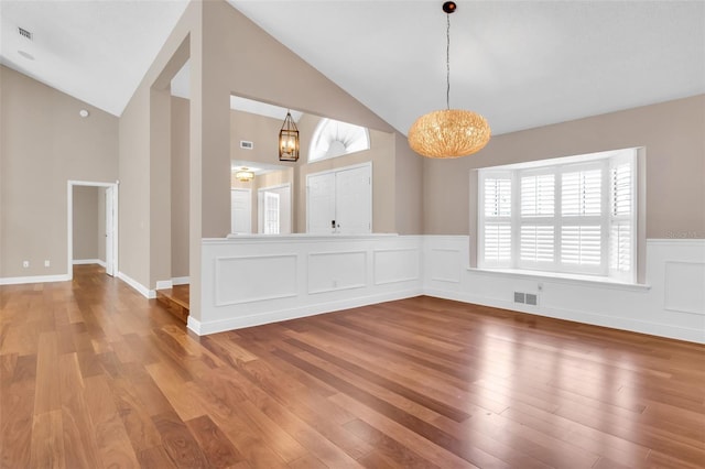 unfurnished dining area with an inviting chandelier, lofted ceiling, and wood-type flooring