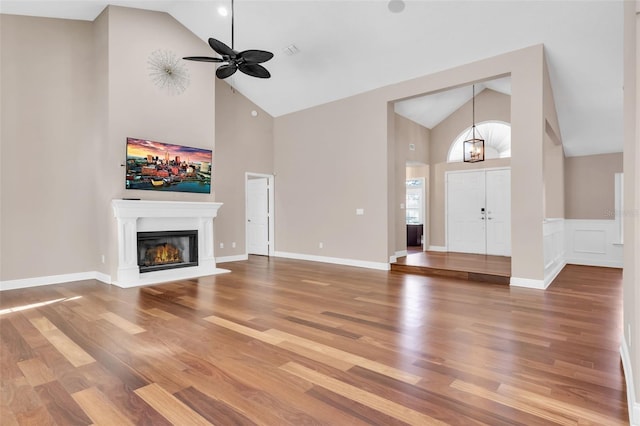 unfurnished living room with hardwood / wood-style flooring, ceiling fan, and high vaulted ceiling