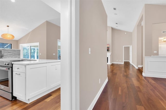 interior space featuring electric stove, white cabinetry, lofted ceiling, and decorative light fixtures