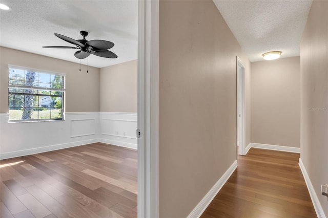 hall with hardwood / wood-style floors and a textured ceiling