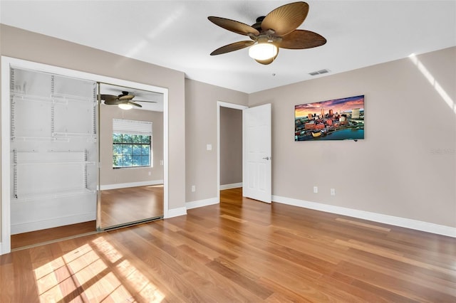 unfurnished bedroom featuring hardwood / wood-style floors, ceiling fan, and a closet