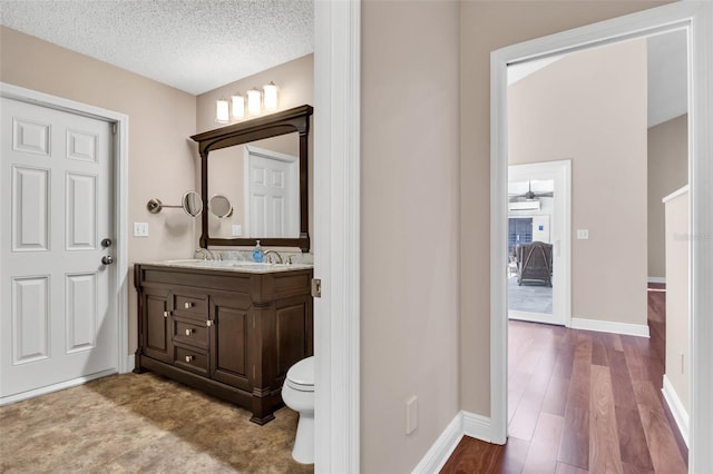 bathroom featuring vanity, wood-type flooring, toilet, and a textured ceiling