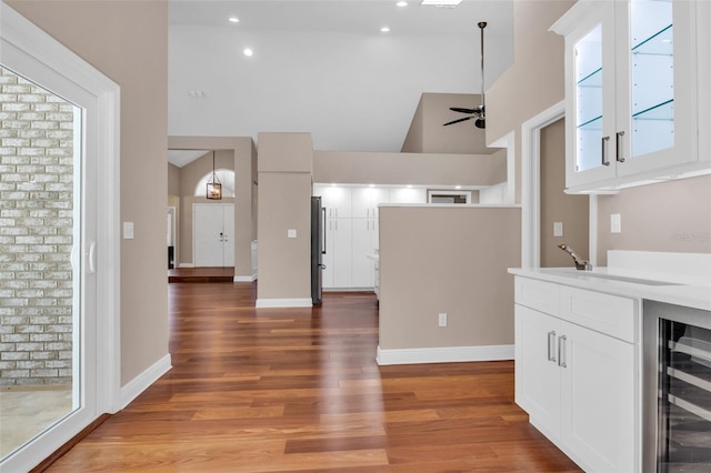 kitchen featuring decorative light fixtures, white cabinetry, wood-type flooring, wine cooler, and ceiling fan