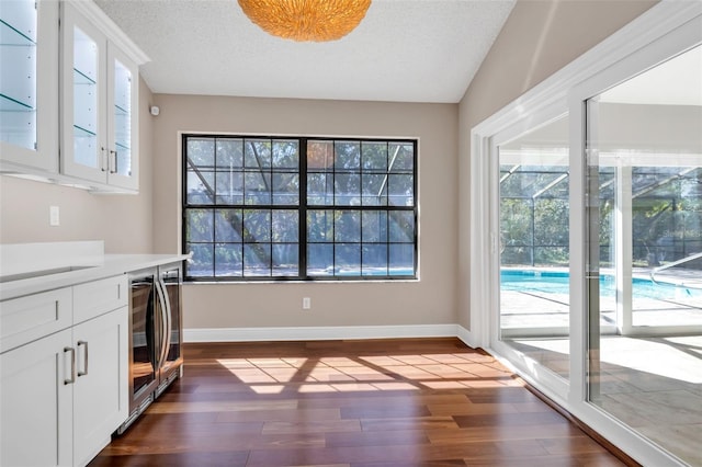 interior space with a textured ceiling, white cabinets, and dark hardwood / wood-style flooring