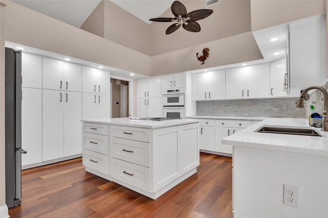 kitchen with a center island, sink, white cabinets, and stainless steel refrigerator