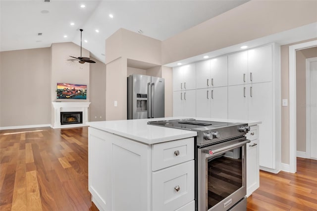 kitchen featuring white cabinetry, lofted ceiling, ceiling fan, stainless steel appliances, and light wood-type flooring