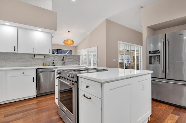 kitchen with tasteful backsplash, hanging light fixtures, high quality appliances, hardwood / wood-style floors, and white cabinets