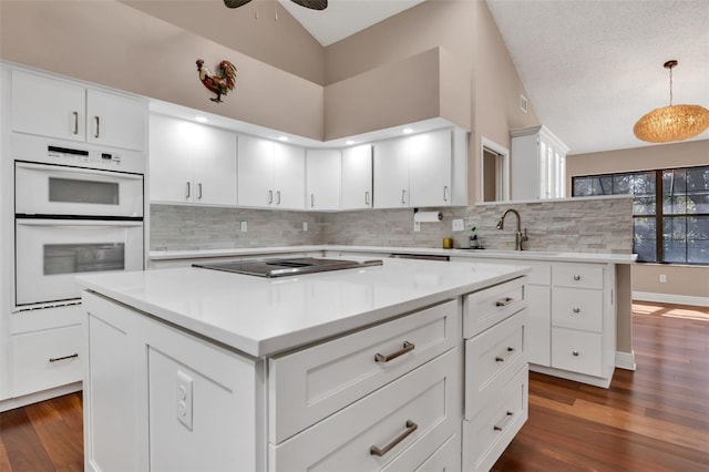 kitchen with black electric stovetop, decorative light fixtures, a center island, and sink