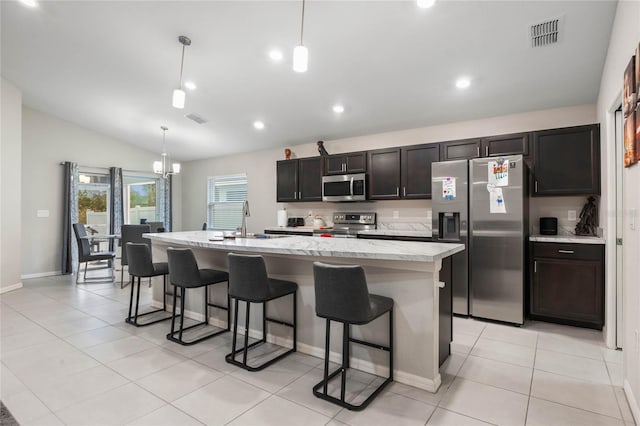 kitchen with appliances with stainless steel finishes, decorative light fixtures, and an island with sink