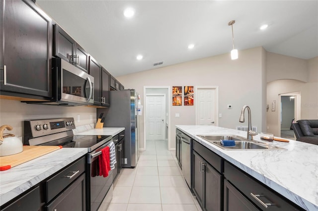 kitchen featuring sink, light tile patterned floors, appliances with stainless steel finishes, decorative light fixtures, and vaulted ceiling