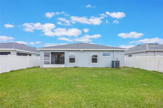 back of property featuring central AC unit, a lawn, and a sunroom