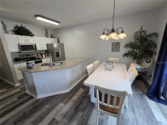 kitchen featuring decorative light fixtures, sink, white cabinets, a kitchen island with sink, and stainless steel appliances