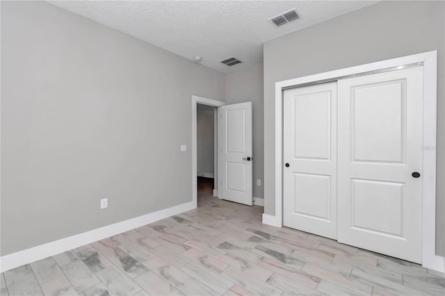 9095 SW 125th Ter, Dunnellon, FL 34432 - unfurnished bedroom featuring a textured ceiling, baseboards, a closet, and light wood-style flooring
