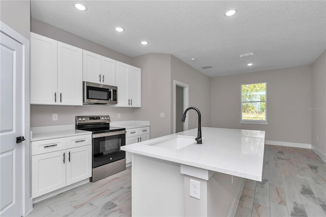 9095 SW 125th Ter, Dunnellon, FL 34432 - kitchen with appliances with stainless steel finishes, a sink, recessed lighting, white cabinets, and a kitchen island with sink