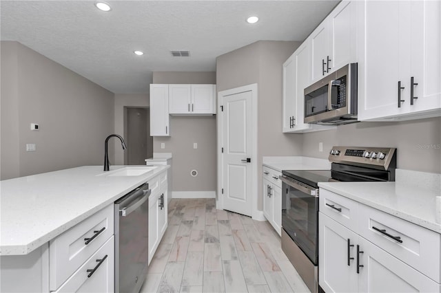 9095 SW 125th Ter, Dunnellon, FL 34432 - kitchen with stainless steel appliances, a sink, recessed lighting, white cabinetry, and light stone counters