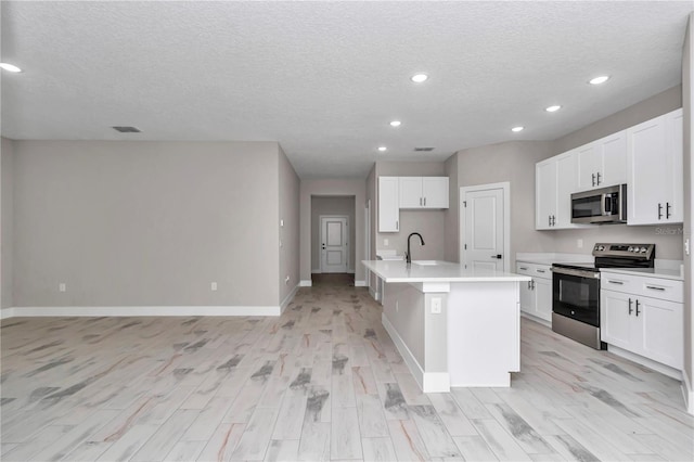 9095 SW 125th Ter, Dunnellon, FL 34432 - kitchen with appliances with stainless steel finishes, baseboards, light wood-style flooring, a center island with sink, and recessed lighting