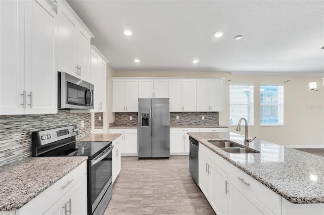 kitchen with a kitchen island with sink, sink, white cabinetry, and stainless steel appliances