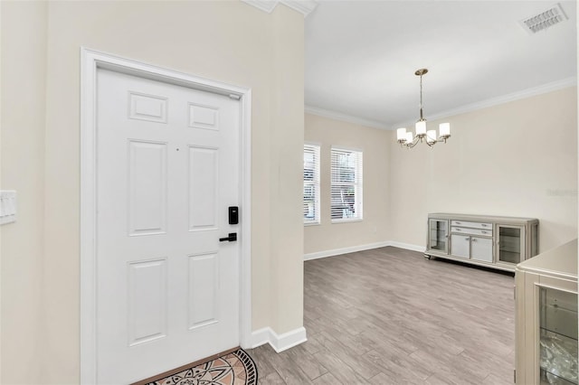 entryway featuring wood-type flooring, ornamental molding, and a chandelier