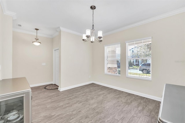 unfurnished dining area with ornamental molding, hardwood / wood-style floors, and an inviting chandelier