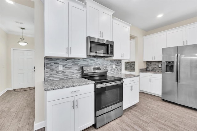 kitchen featuring white cabinetry, stainless steel appliances, decorative light fixtures, and light stone counters