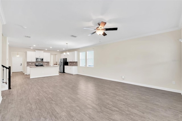 unfurnished living room with hardwood / wood-style flooring, ornamental molding, and ceiling fan