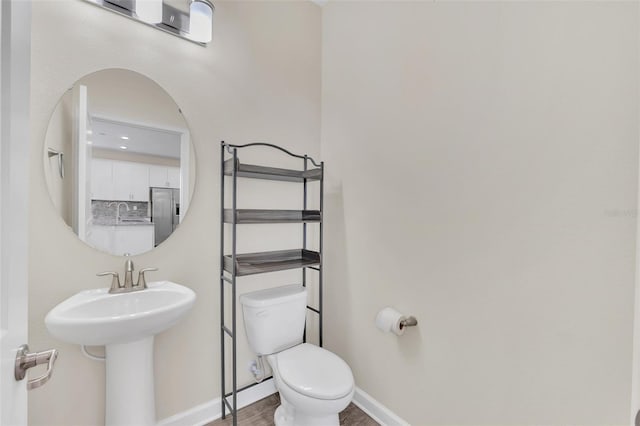 bathroom featuring wood-type flooring, toilet, and sink