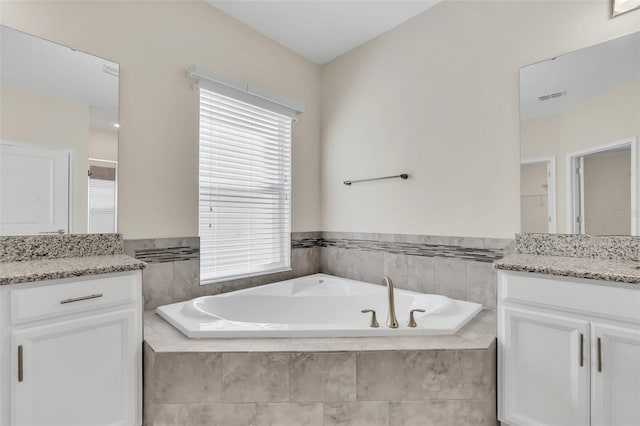 bathroom with vanity and tiled tub