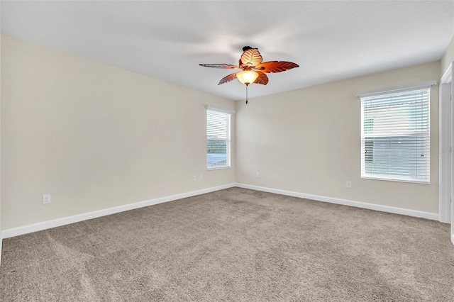 carpeted spare room featuring ceiling fan and a wealth of natural light