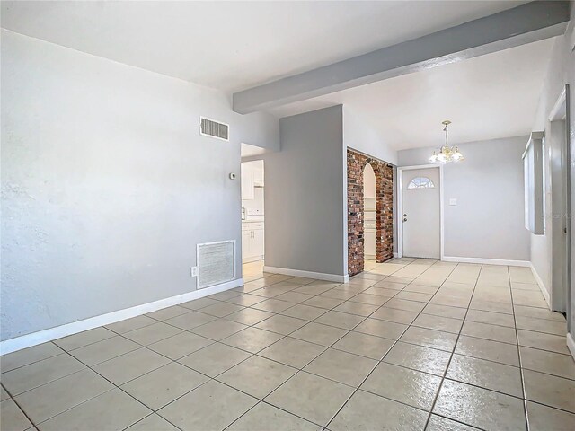 tiled spare room featuring lofted ceiling with beams and an inviting chandelier