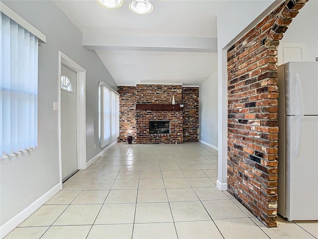 unfurnished living room featuring light tile patterned flooring, brick wall, lofted ceiling with beams, and a brick fireplace