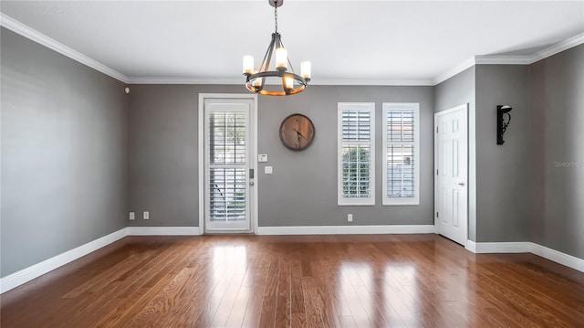 empty room with crown molding, dark hardwood / wood-style floors, and a notable chandelier