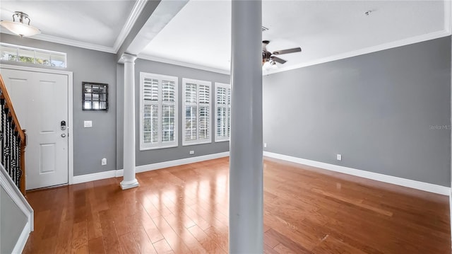 entrance foyer featuring decorative columns, ornamental molding, wood-type flooring, and ceiling fan