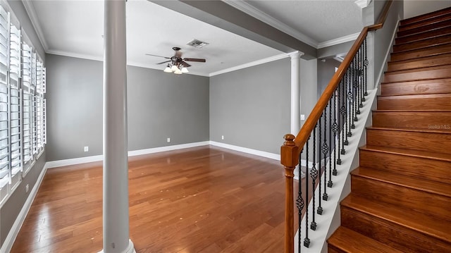 staircase featuring ornate columns, ornamental molding, hardwood / wood-style flooring, and ceiling fan