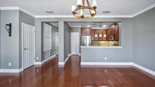 kitchen with an inviting chandelier, hanging light fixtures, appliances with stainless steel finishes, dark hardwood / wood-style flooring, and kitchen peninsula