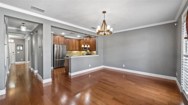 kitchen with an inviting chandelier, hanging light fixtures, appliances with stainless steel finishes, dark hardwood / wood-style flooring, and kitchen peninsula