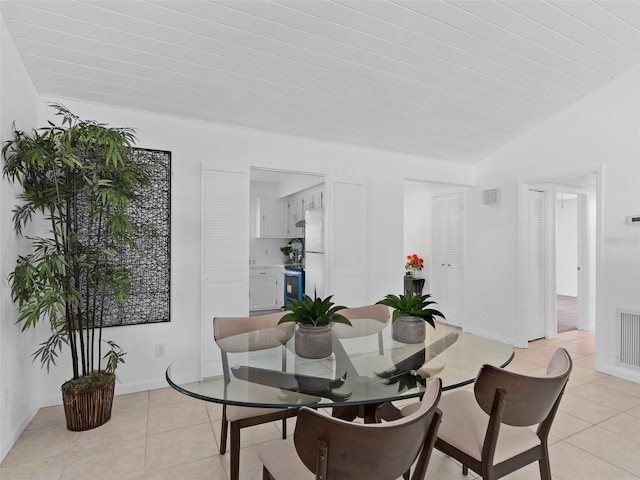 dining area featuring lofted ceiling and light tile patterned floors