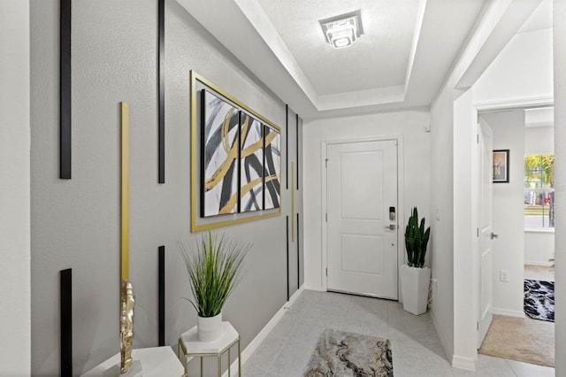 tiled entryway featuring a tray ceiling