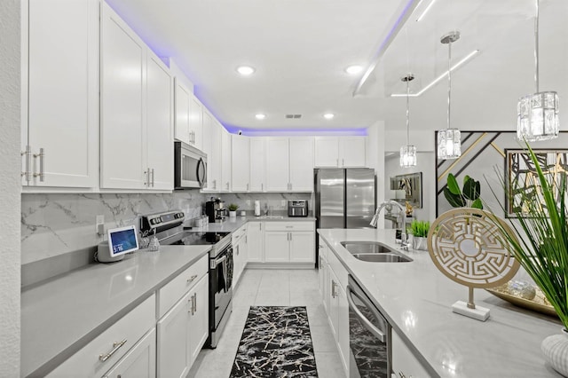 kitchen with sink, appliances with stainless steel finishes, decorative backsplash, white cabinets, and decorative light fixtures