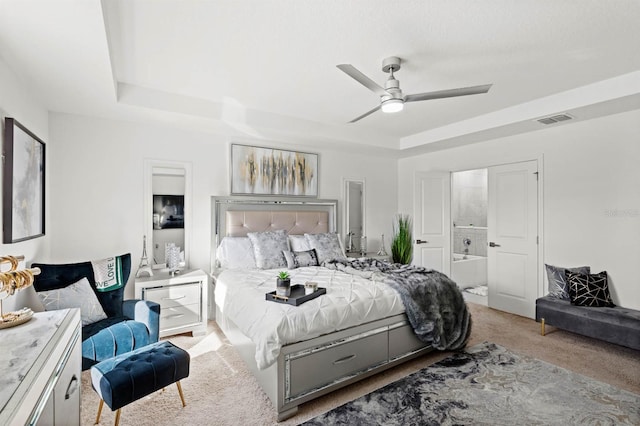 carpeted bedroom featuring connected bathroom, a raised ceiling, and ceiling fan