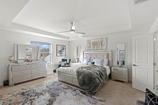 carpeted bedroom with a tray ceiling and ceiling fan