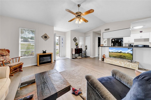 living room featuring lofted ceiling, light hardwood / wood-style floors, and ceiling fan